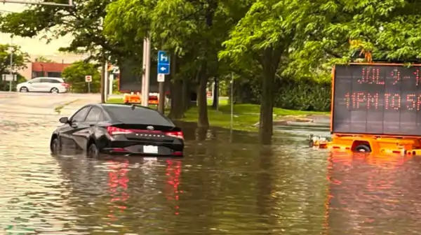 A car attempts to travel along a flooded road in Ward 9 Ottawa